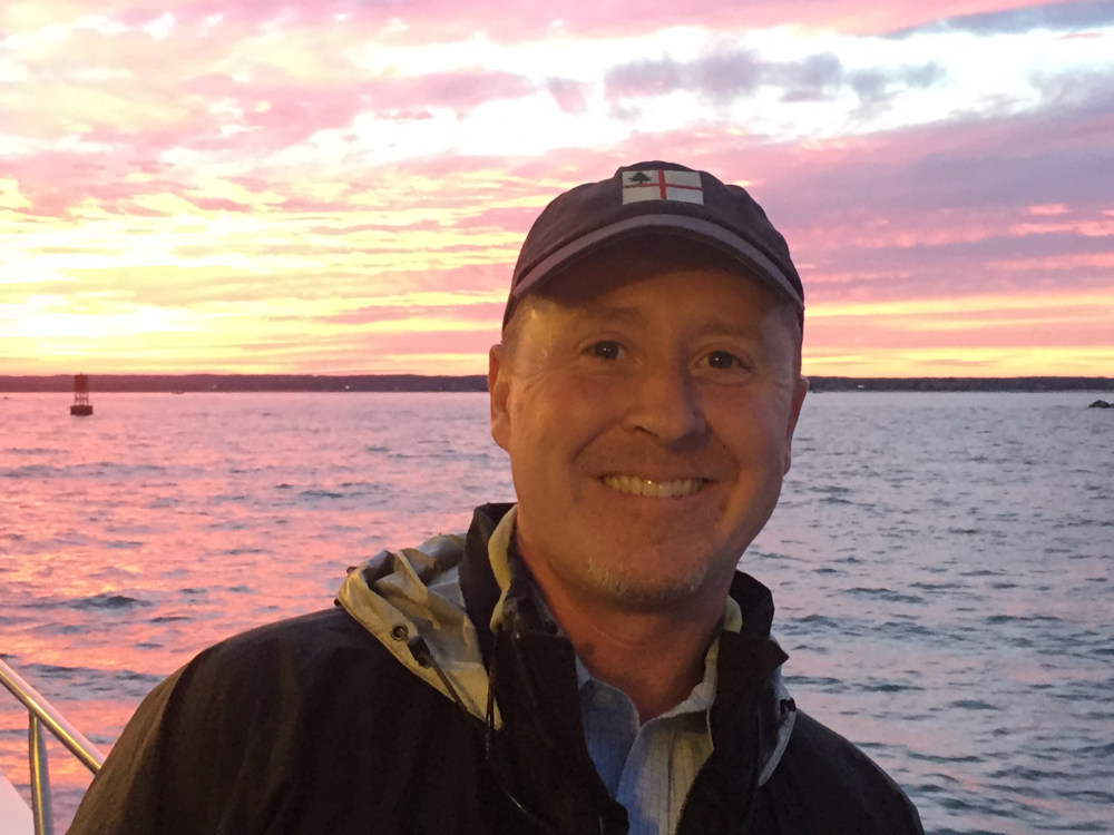 Mike Carroll smiling with sunset-water behind him